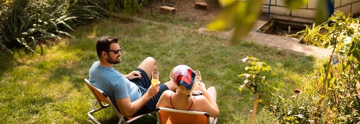 Zwei Personen entspannen sich auf Liegestühlen im Garten.
